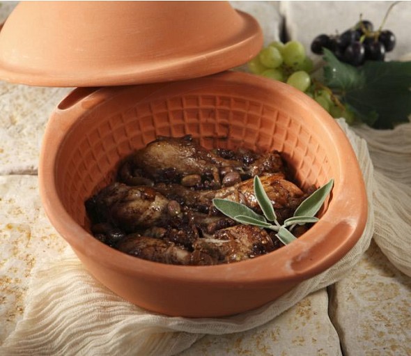 Chicken drumsticks in a ceramic pot with raisins and molasses